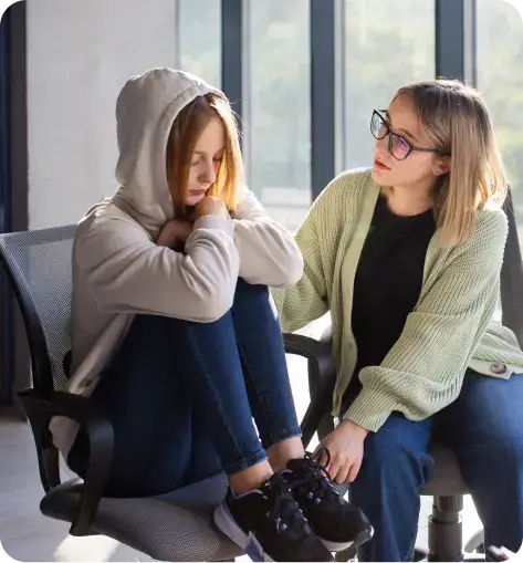 sad girl wearing hoodie with a woman comforting her